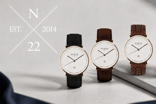 North Twentytwo-logotyp N 22 est. 2014 bredvid tre armbandsur med vit urtavla och guldfärgad boett, med svart, brunt och flätat läderarmband